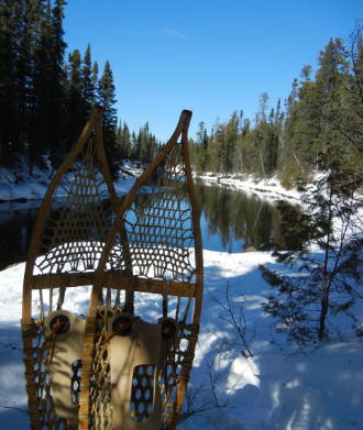 snowshoes in front of a tree-lined lake