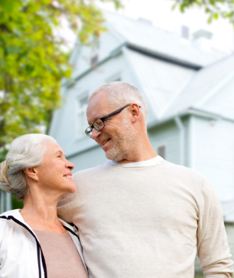 Senior couple stands outside a home